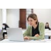 Female student in green sweater studying on a laptop