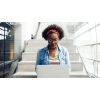 Female student on a laptop at the bottom of stairs
