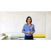 Female teacher standing with notebook in front of a whiteboard