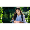 Female student with white glasses studying a notebook outside
