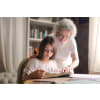 Older woman guiding a young woman as she reads