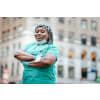 Woman wearing nursing scrubs, posing for a photo outside the hospital