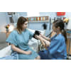 Female nurse taking a patient's blood pressure while she's sitting on a hospital bed