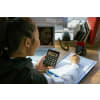 Woman holding a calculator while writing down notes