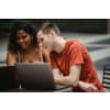 Two students studying outdoors with their laptop