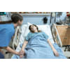 Female nurse checking on a female patient that is lying on a hospital bed