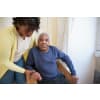 Female nurse assisting an elderly man out of a chair