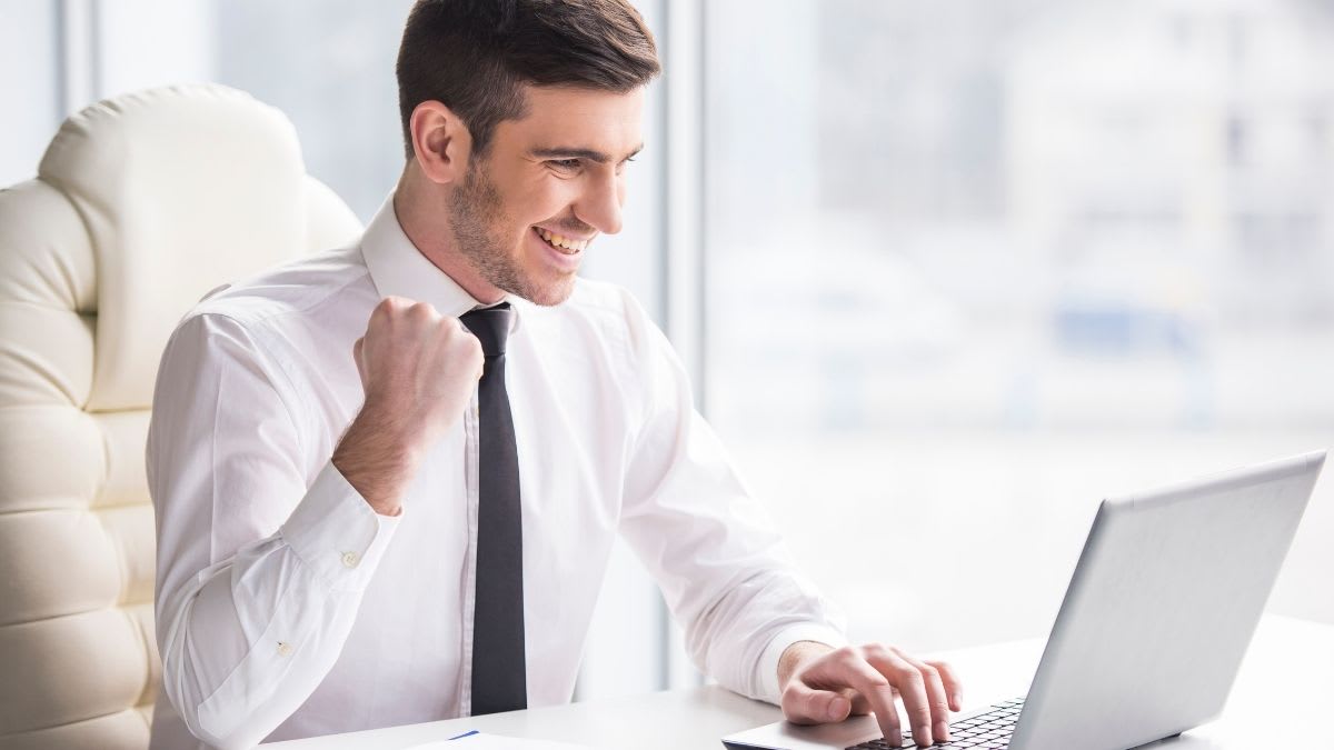 Male student in a suit sitting down and celebrating