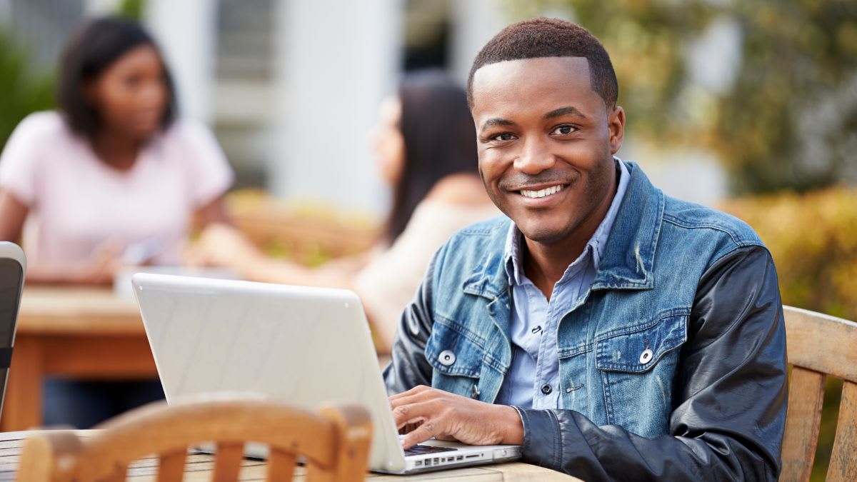 Male student studying outside on a laptop