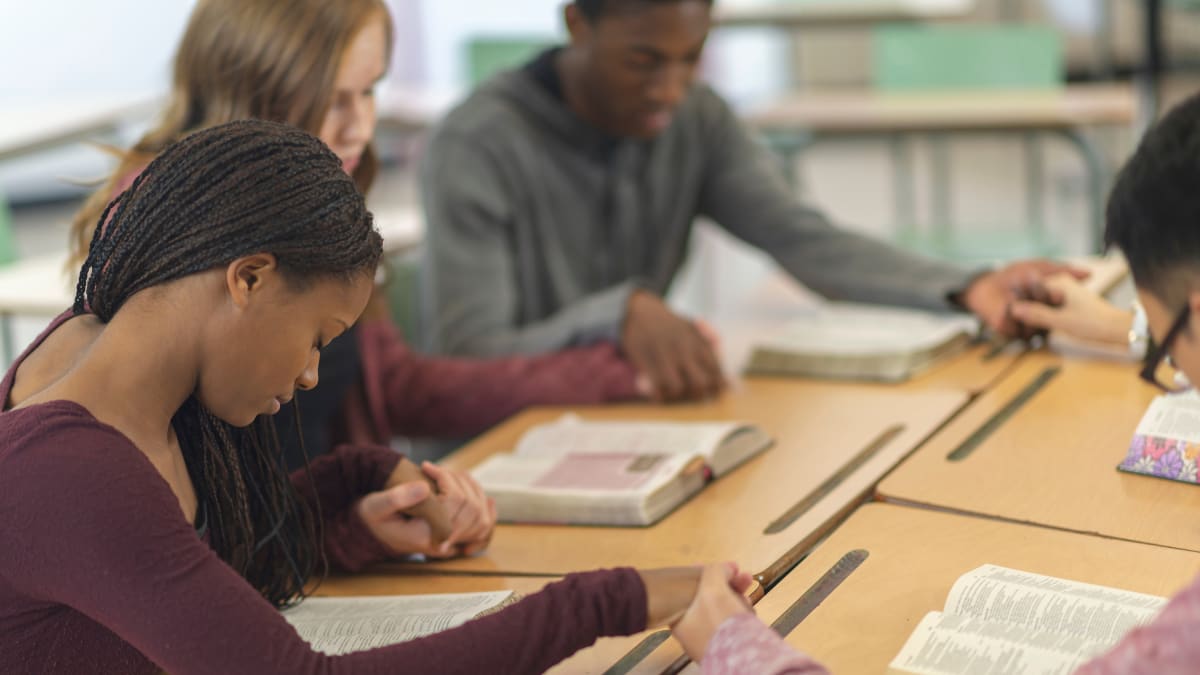 Students praying in a classroom