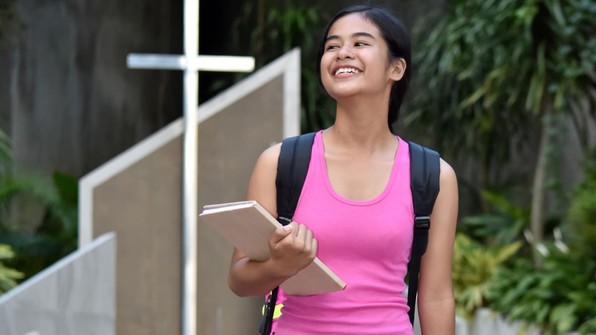 Student standing in front of a Christian cross