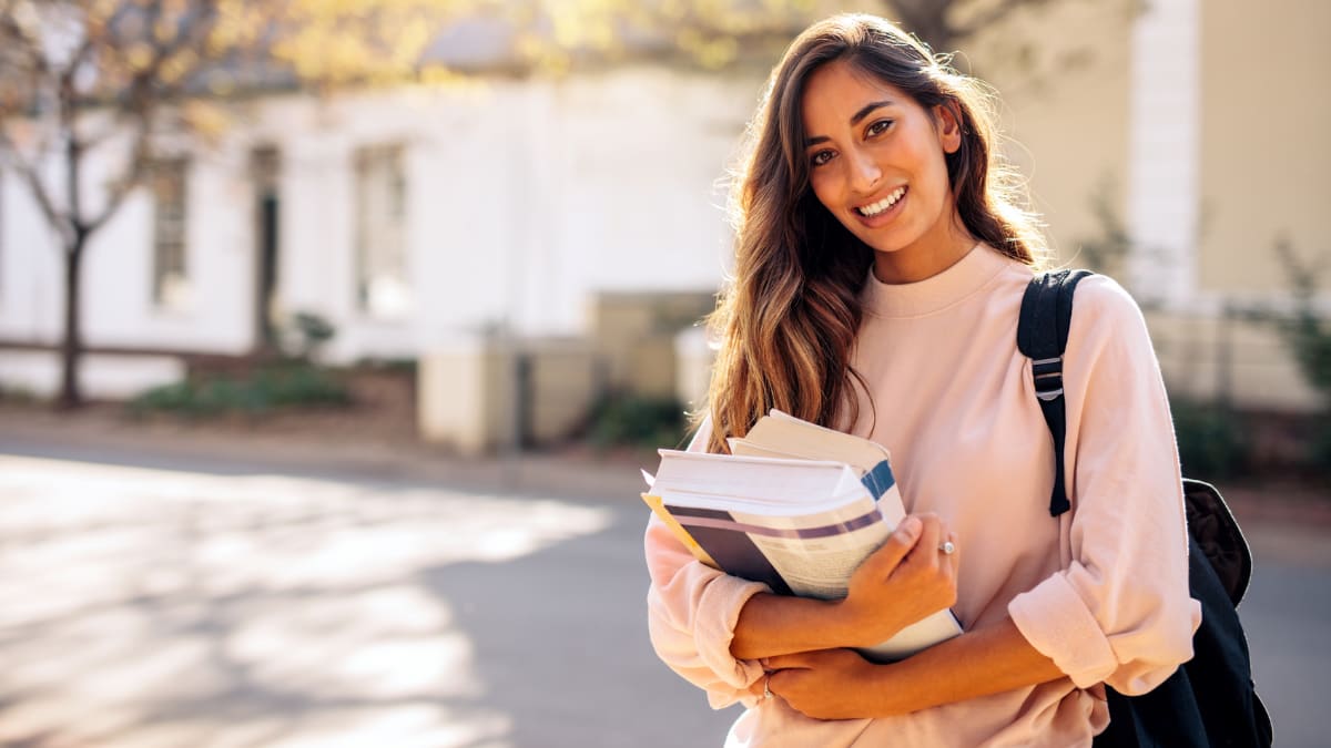 Female student smiling outside with textbooks