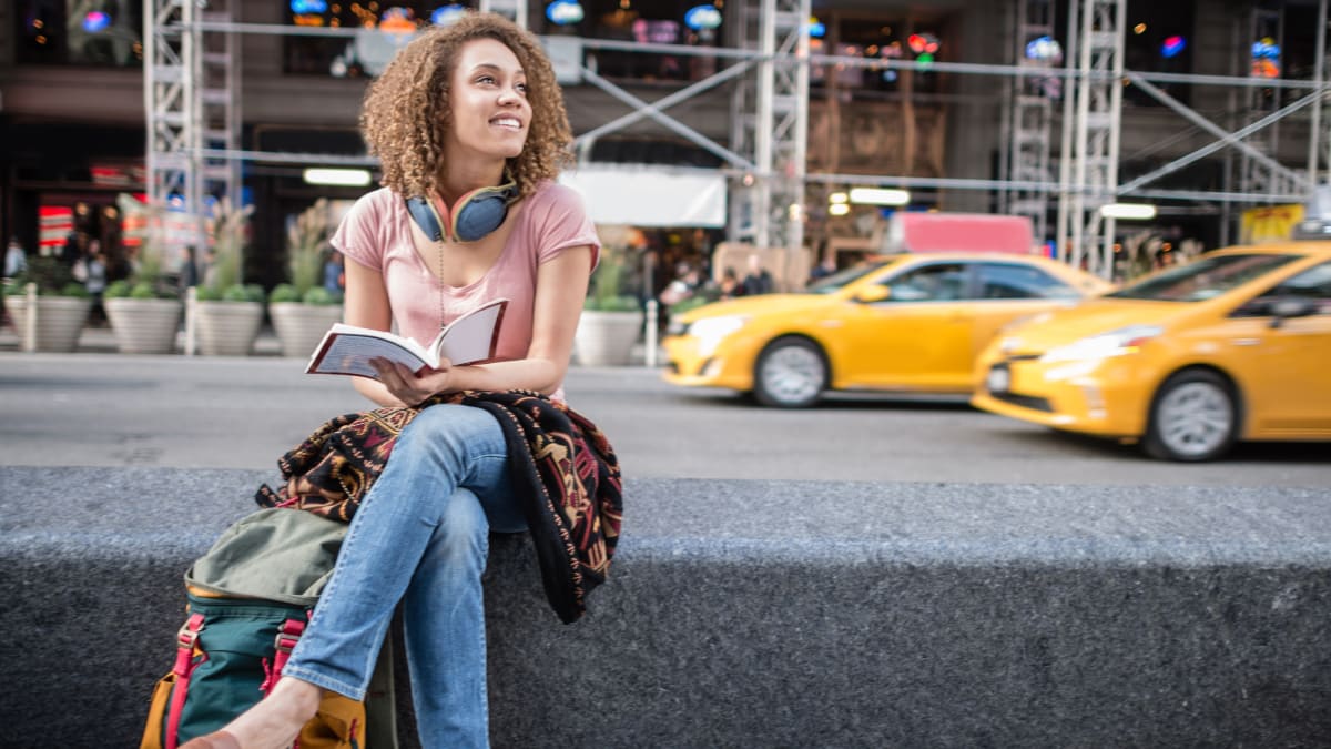 Student studying near two yellow taxis