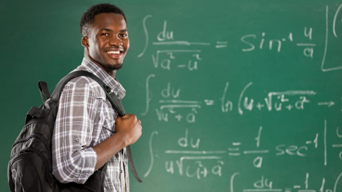 Smiling male student in front of a chalkboard