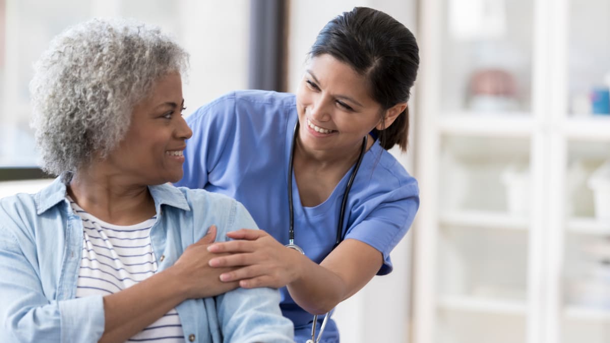 Nurse helping woman with white hair