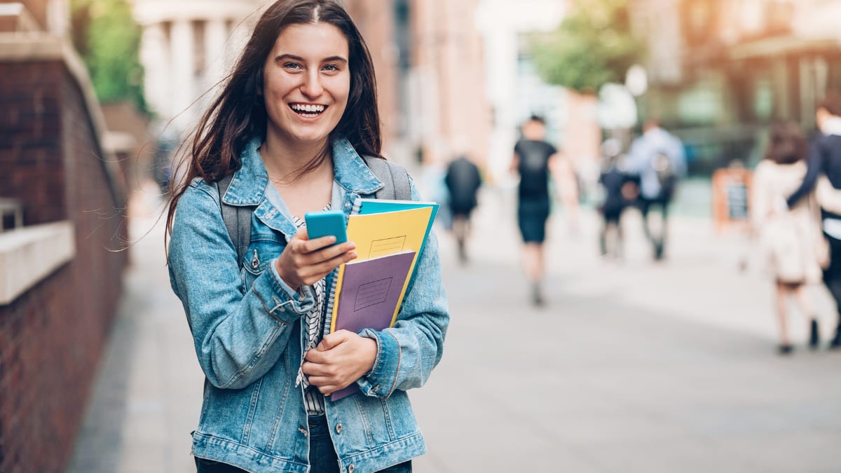 Student holding notebooks and laughing