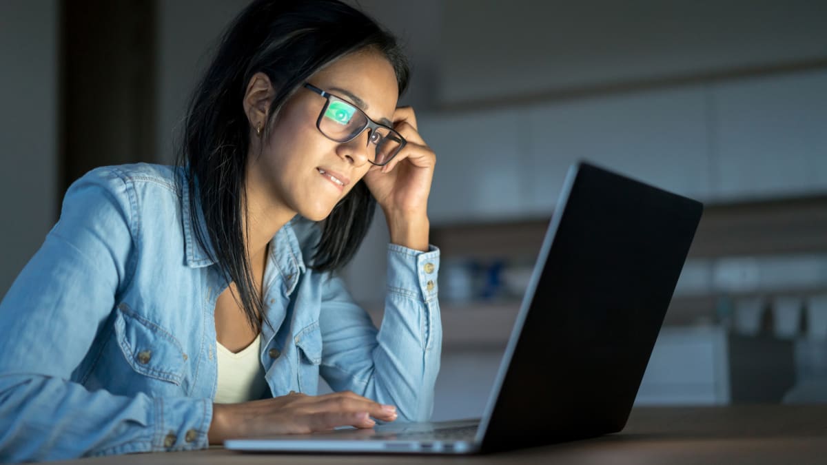 Female student with glasses working on a laptop in the dark