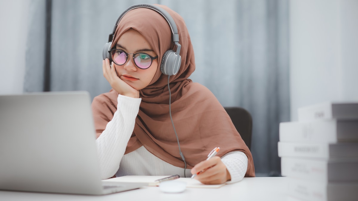 Student with glasses taking notes on a laptop