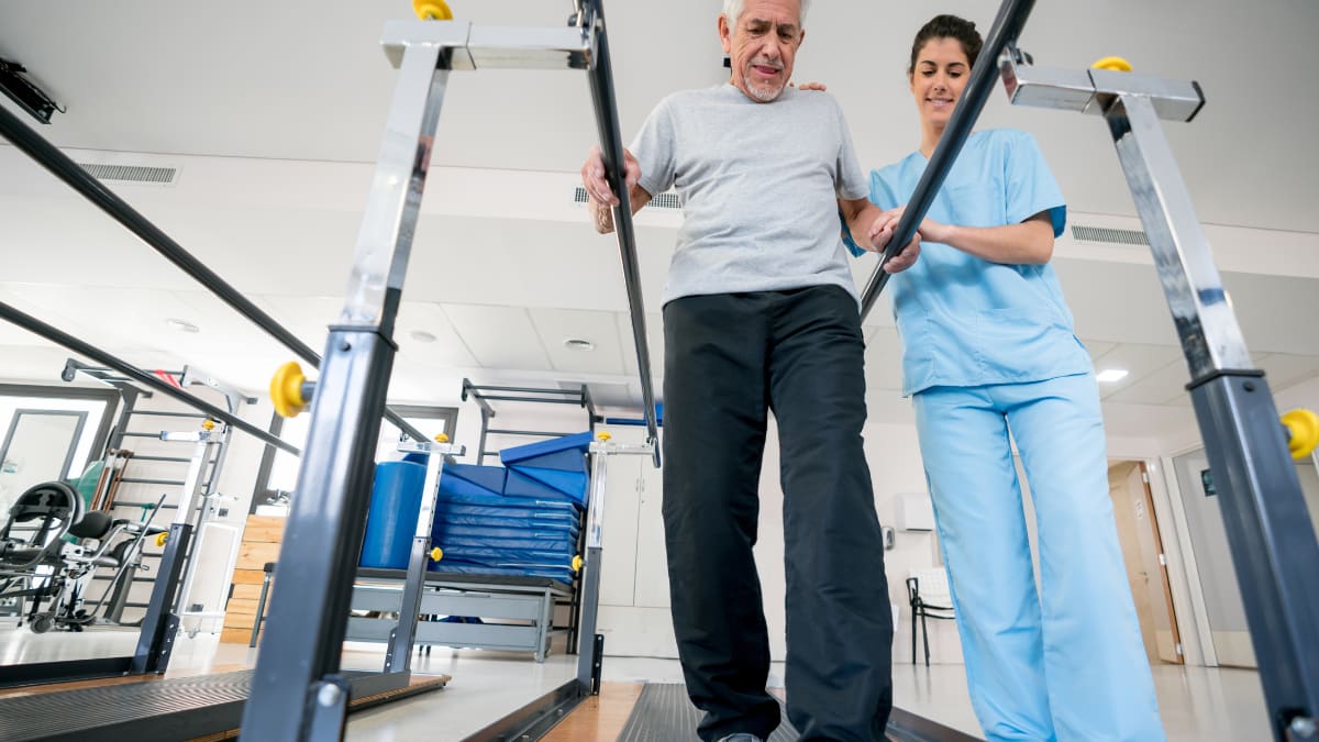 Occupational therapist helping an old man walk