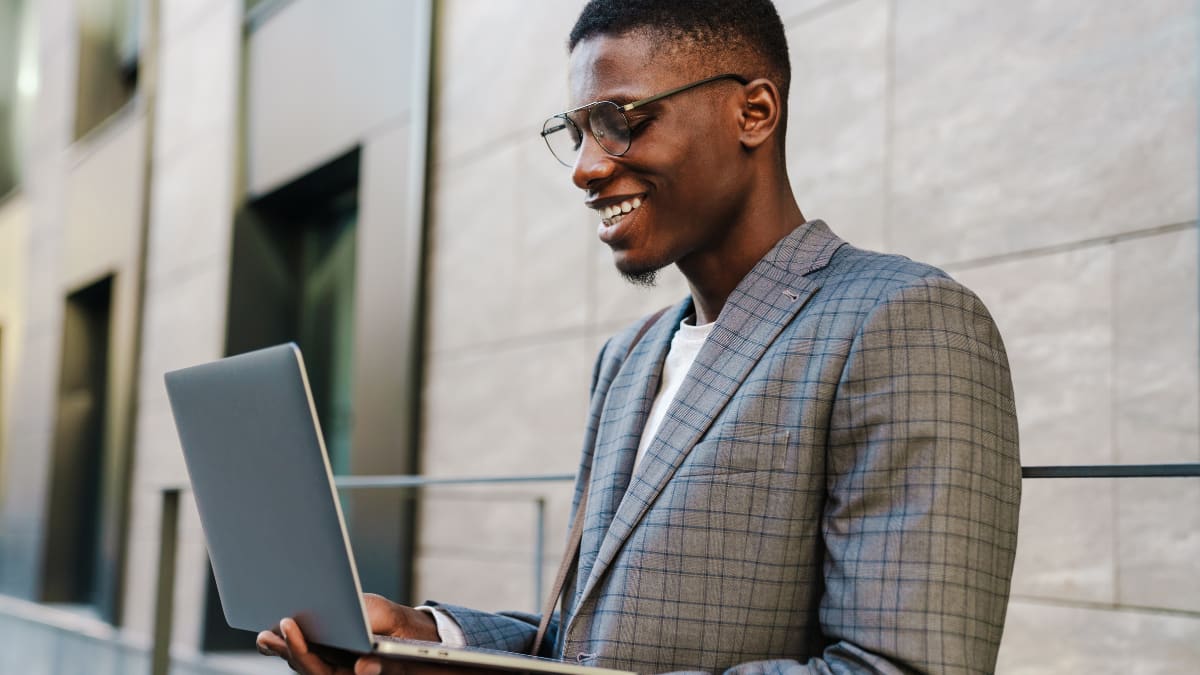 Smiling man with glasses on laptop