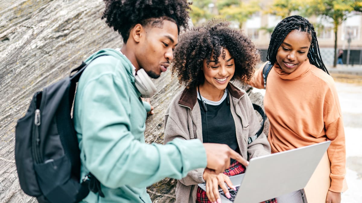 Three students studying next to a boulder