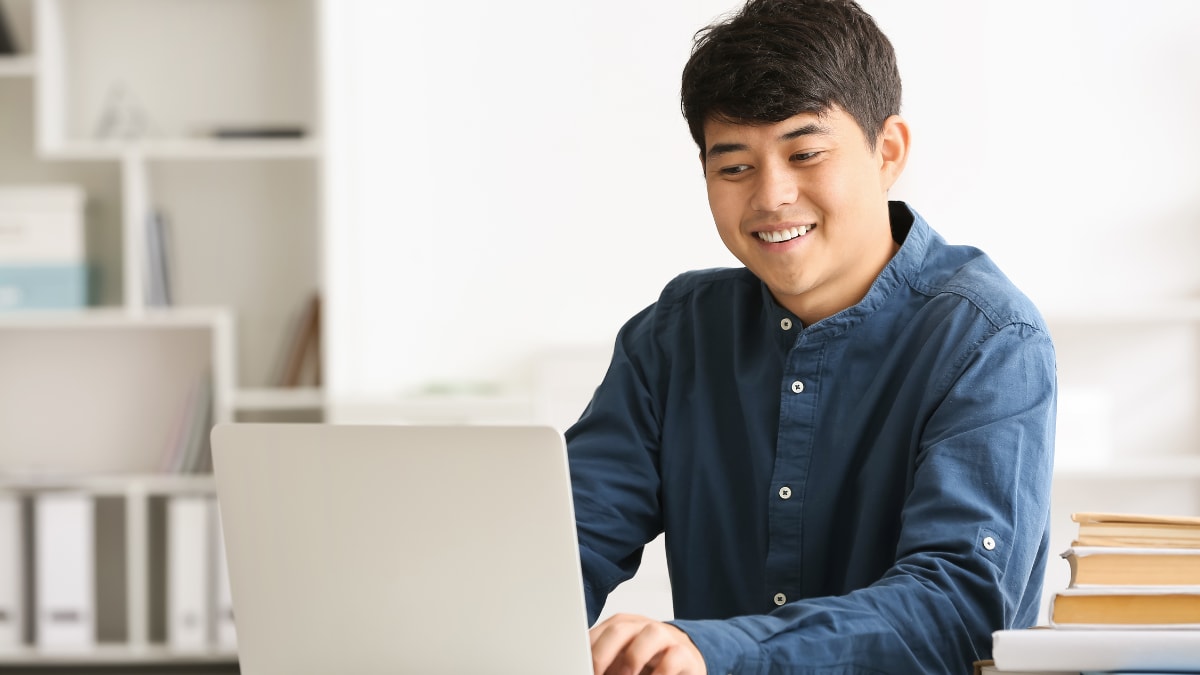 Male student smiling at a laptop