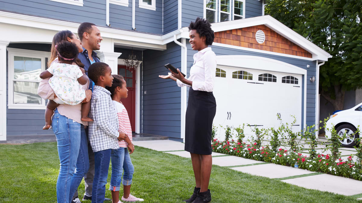 Real estate agent with a family in front of a house