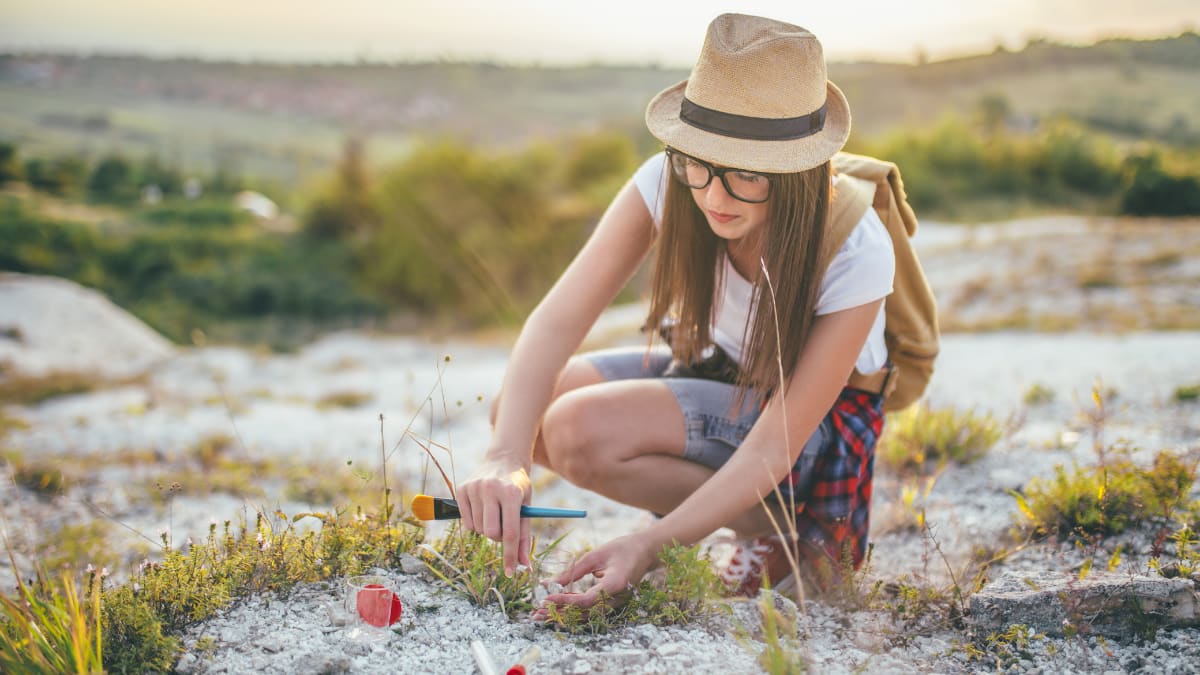 Woman with glasses studying plants outside