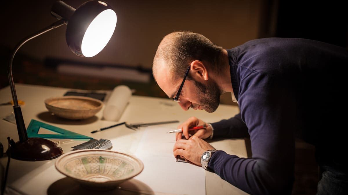 Man using a math compass at a desk