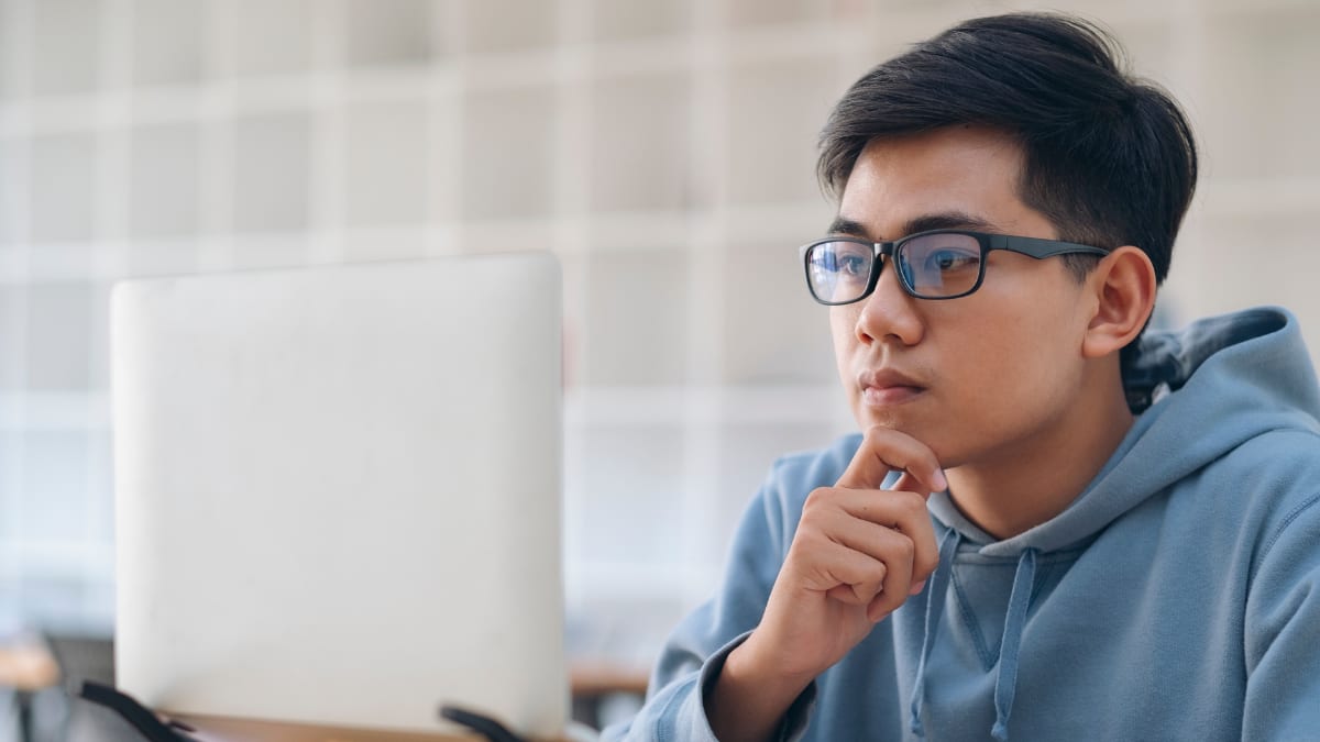 Student thinking next to a laptop