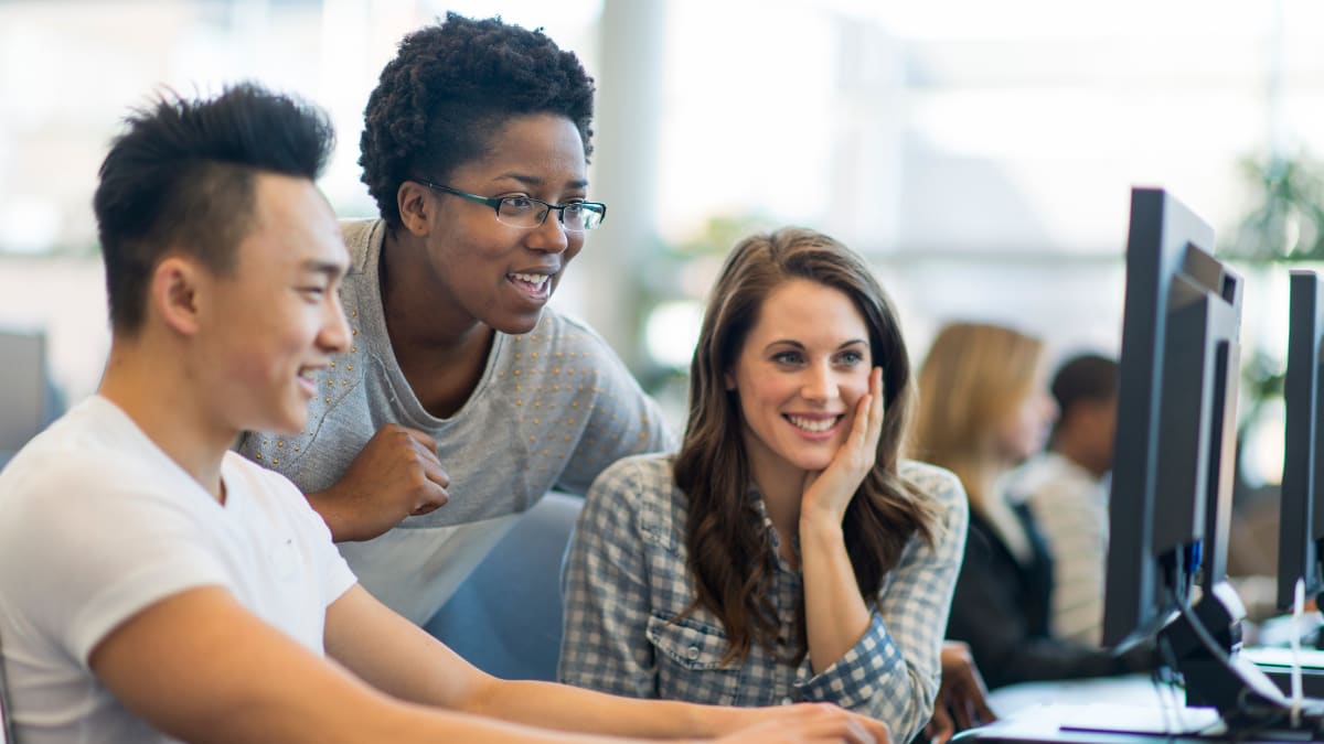 Three students happily working at a computer