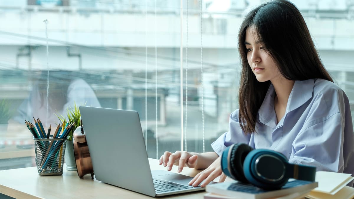 Woman coding next to a window