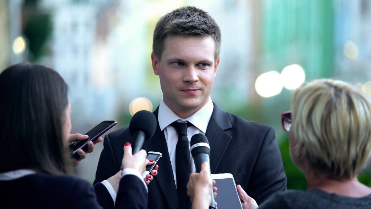 Journalists interviewing a man in a suit