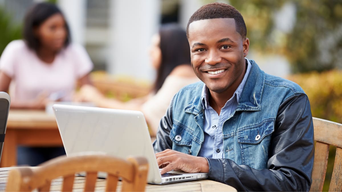 Student smiling at table outside