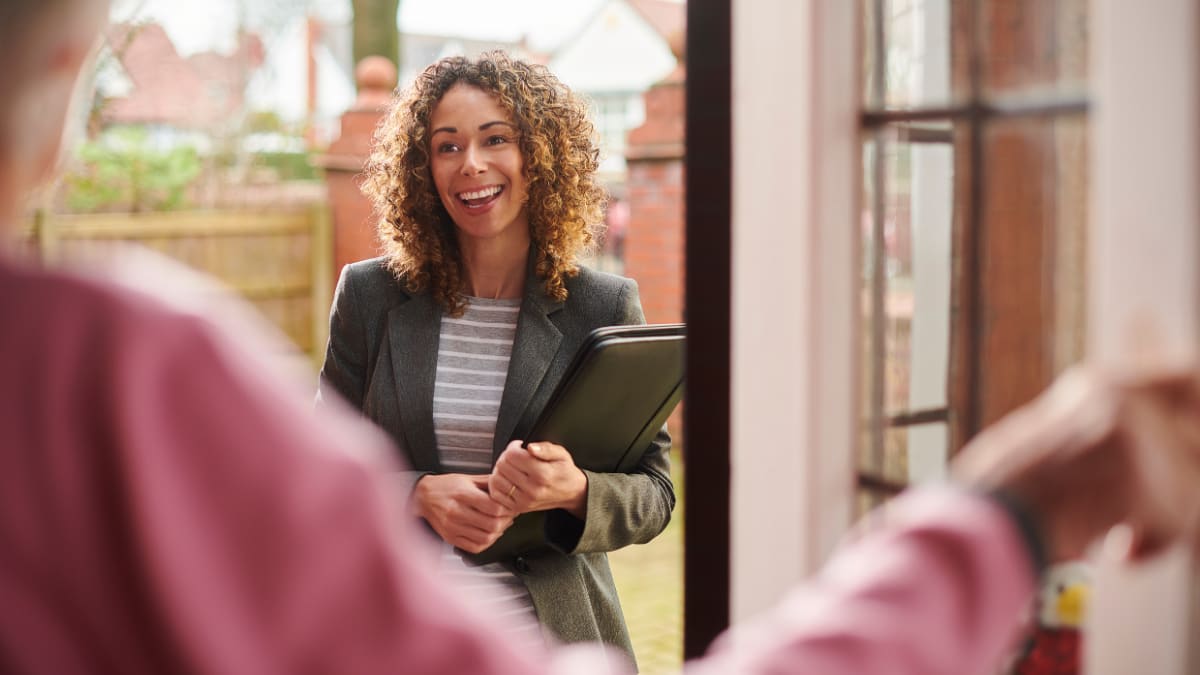Smiling woman holding a binder and standing in a doorway