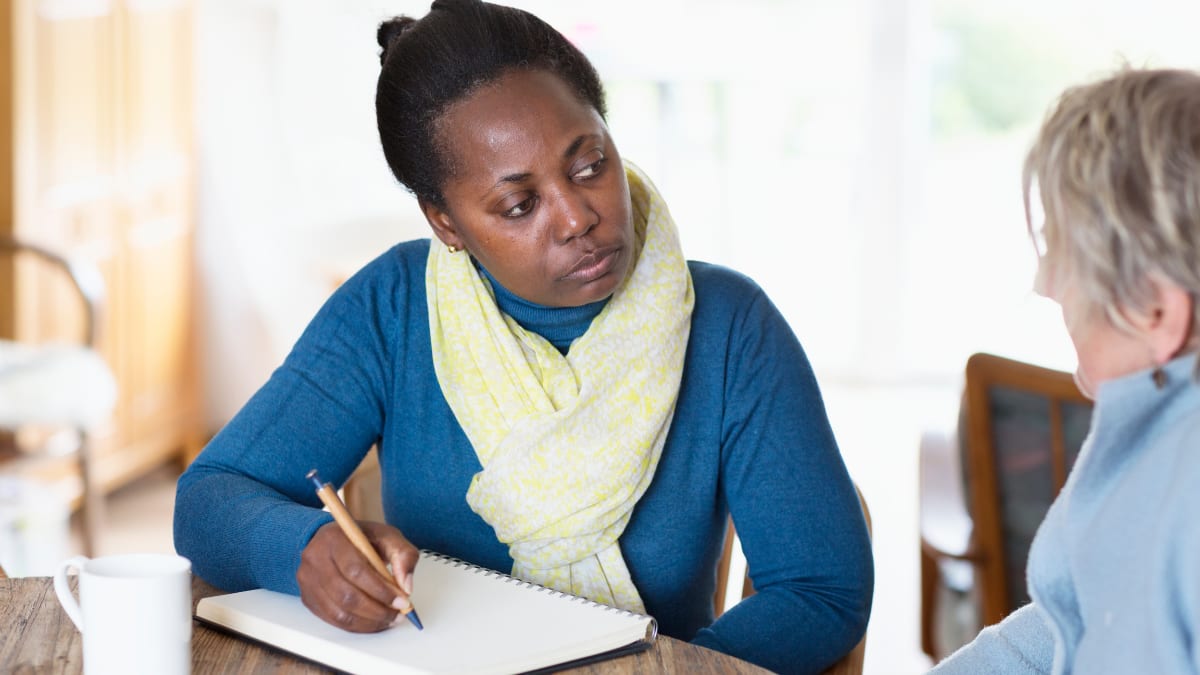 Woman holding pencil and listening to older woman