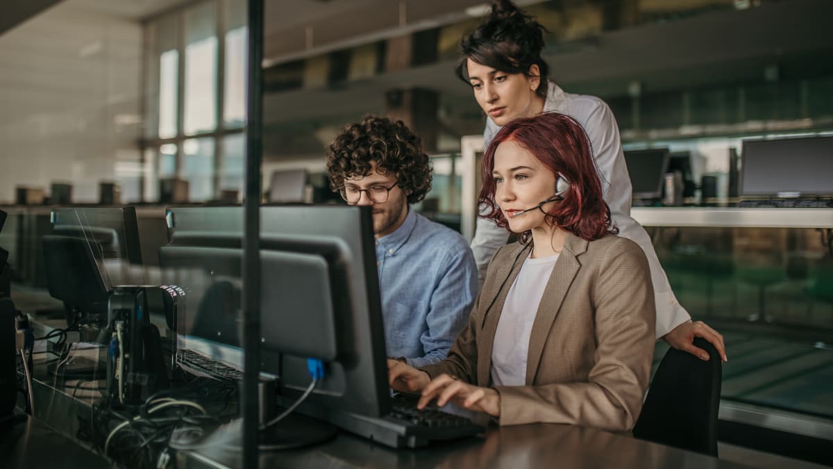 Three professionals working on a computer