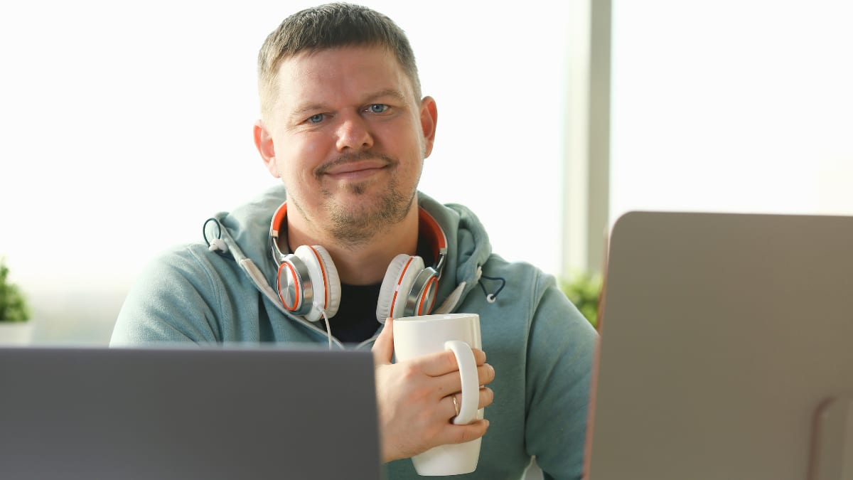 Man smiling and holding a cup of coffee