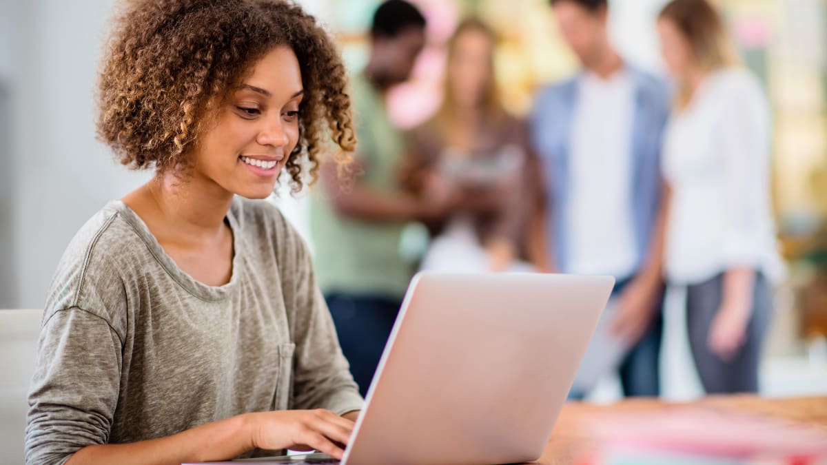 Student smiling at a laptop