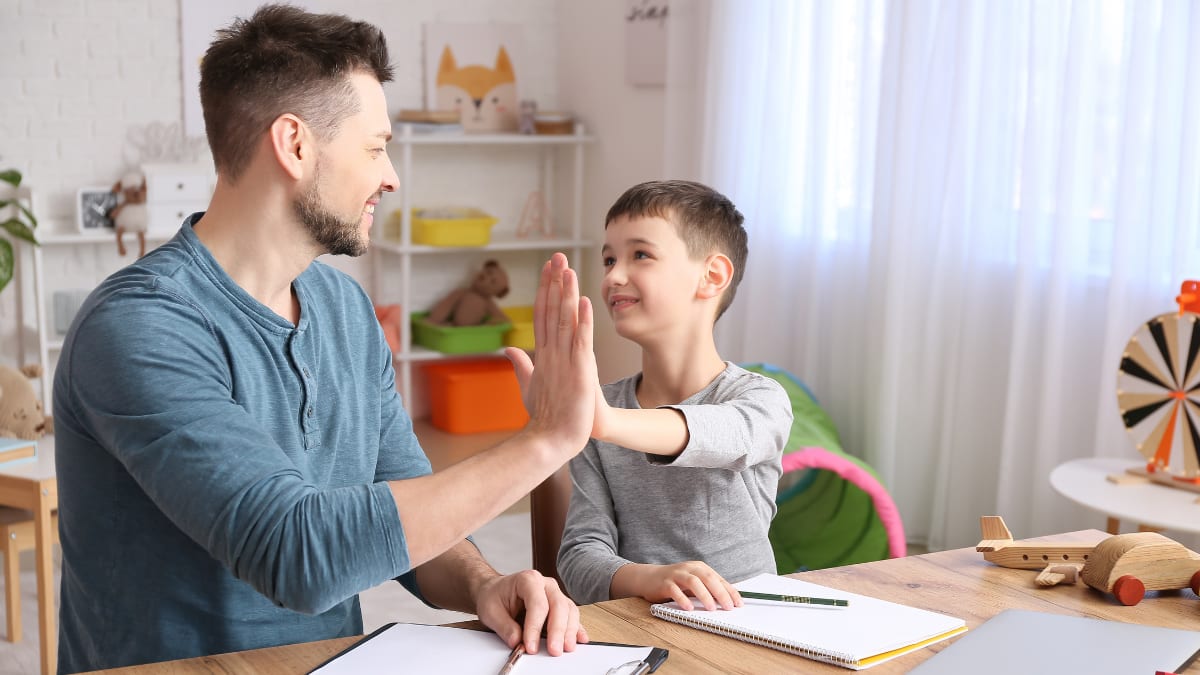 Male psychologist high-fiving a boy