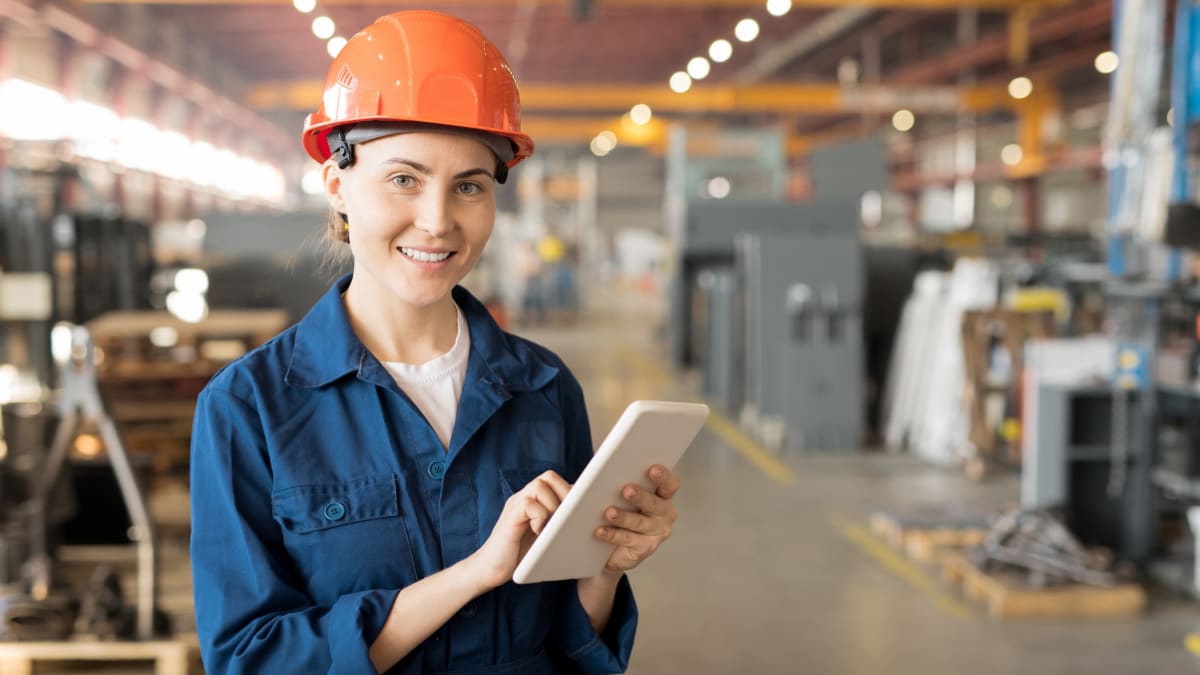 Woman standing in a warehouse with a hardhat