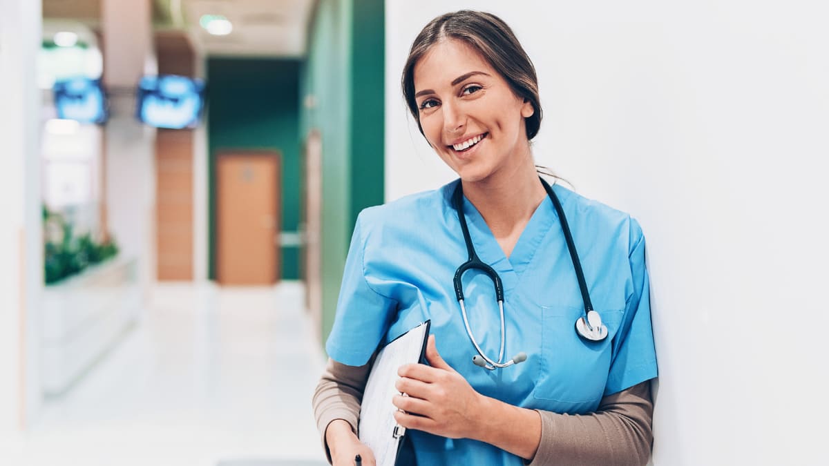 Female nurse smiling with clipboard and stethoscope