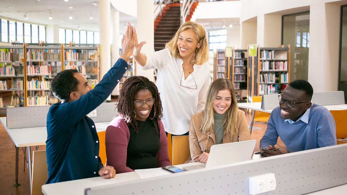 Teacher high-fiving a student in a library