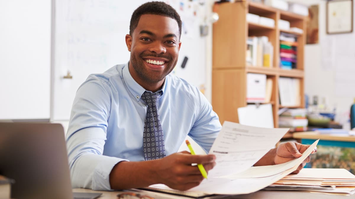 Teacher smiling and grading tests