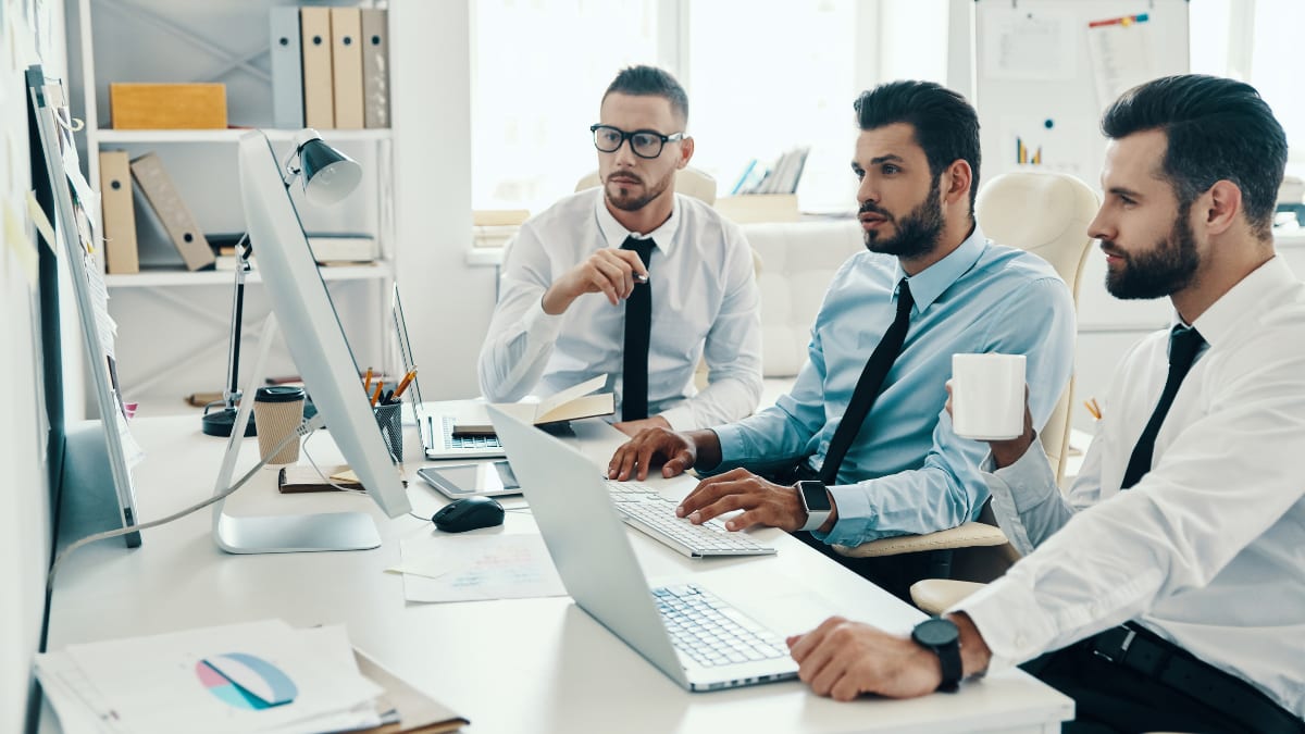 Three business professionals looking at a computer monitor