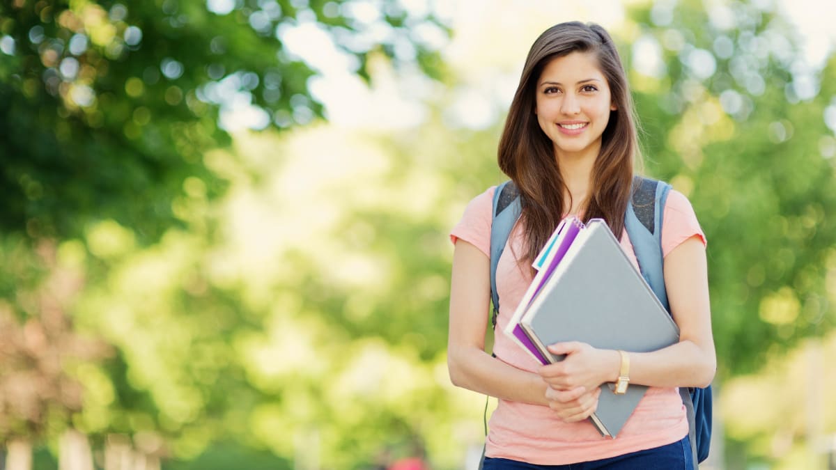 Smiling female student with notebooks