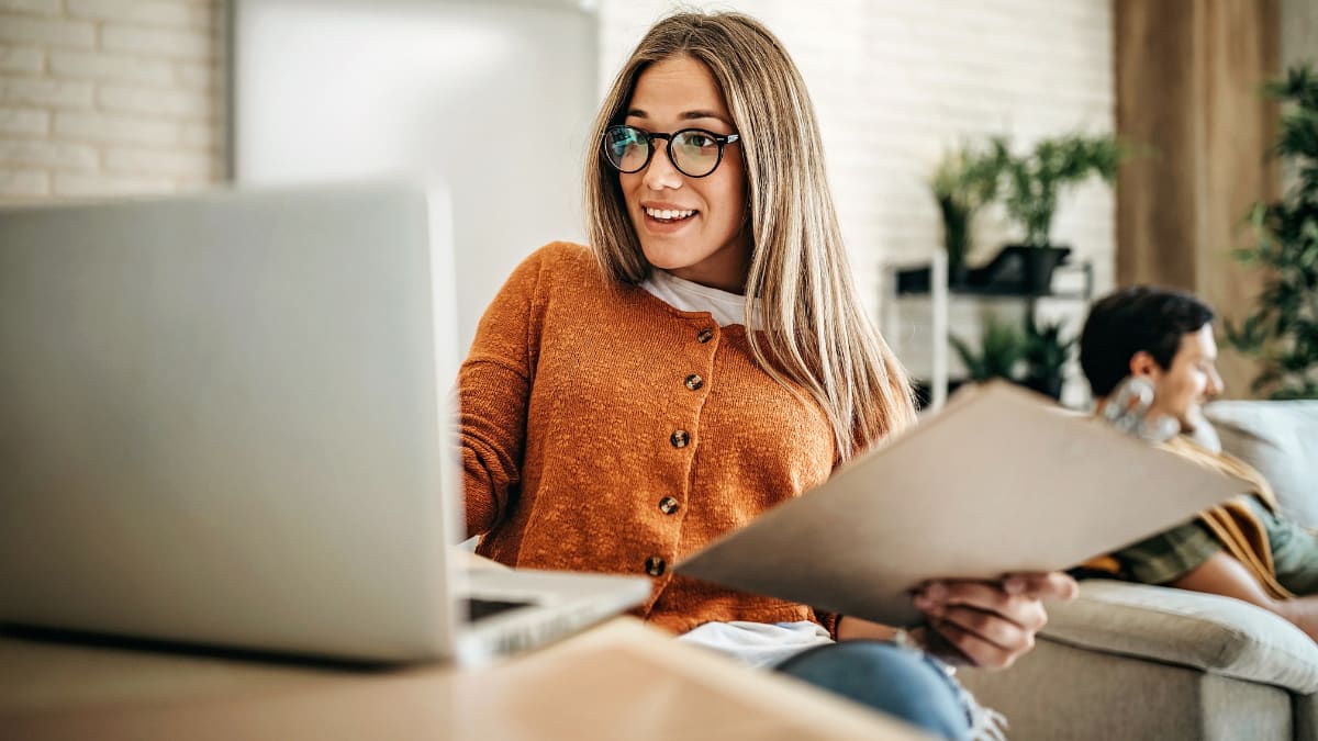 Female student with glasses smiling at a laptop