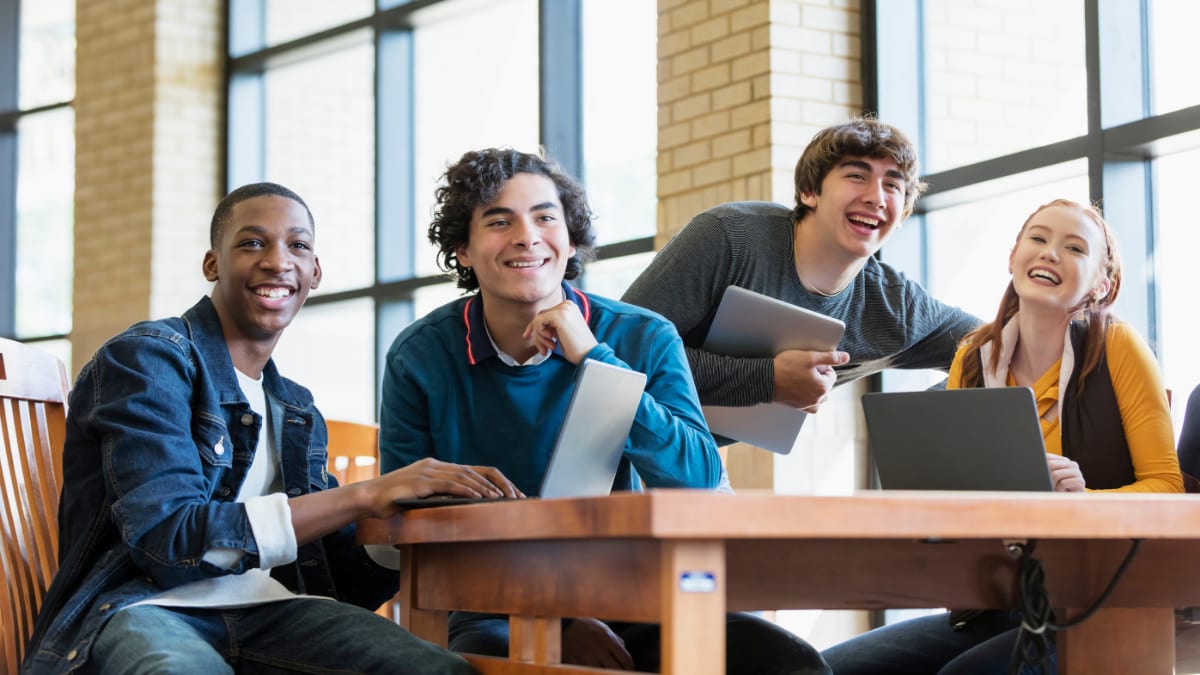 Four smiling students at a desk