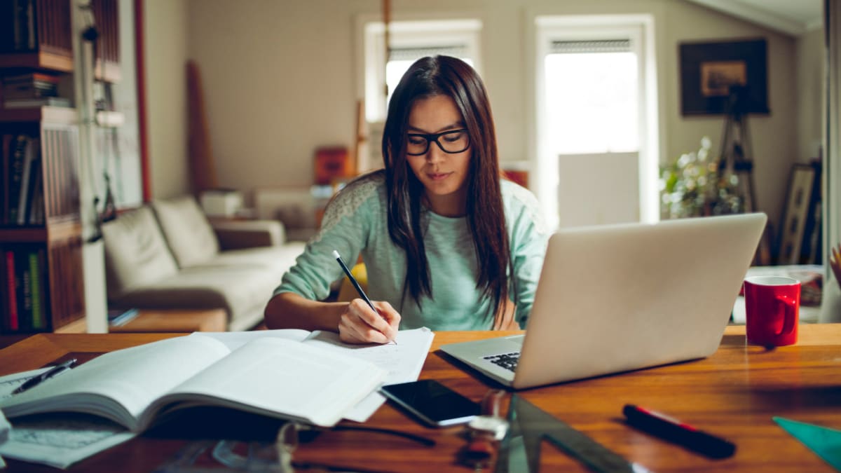 Female student taking notes in a living room