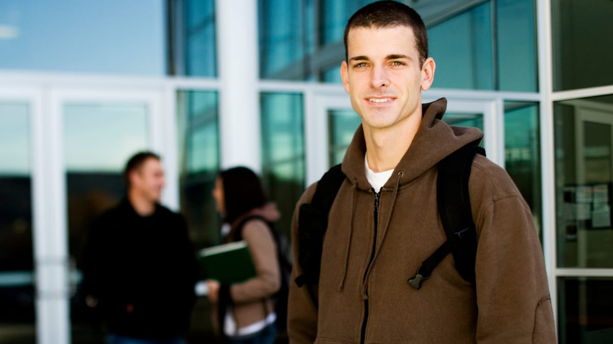 Male student with backpack in front of a building